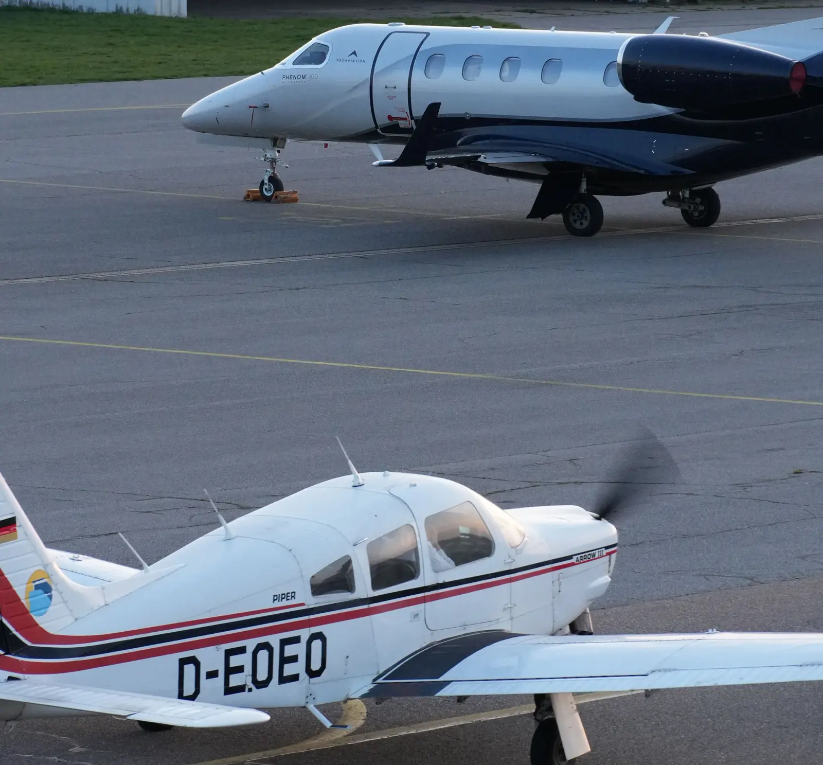 A Piper Arrow taxiing past a Phenom 300 jet