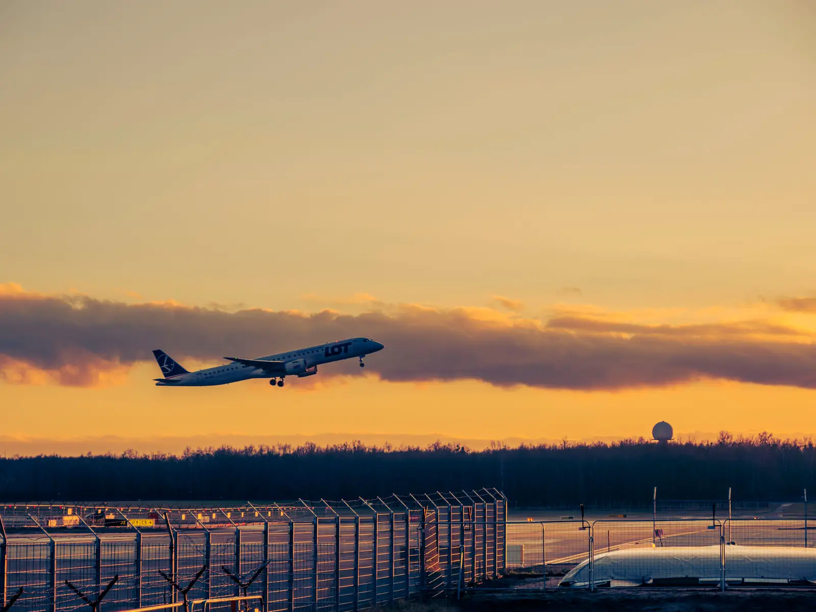 Aircraft lifting off a runway at sunset